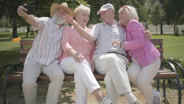 Two Cute Mature Couples Sitting on the Bench Together