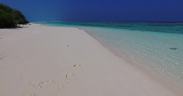 Wide angle fly over tourism shot of a sandy white paradise beach and aqua blue ocean background in h