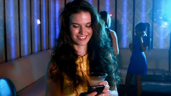 Smiling woman with cocktail drink typing a message