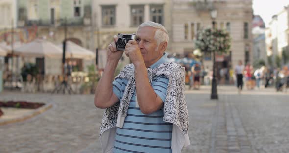 Senior Male Tourist Exploring Town and Makes a Photo with Retro Photo Camera