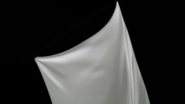 White fabric flowing on black background, Slow Motion