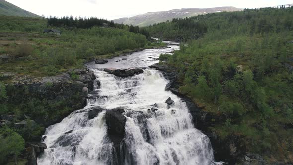Aerial View Of River Cascading Down Rocks Surrounded By Green Wilderness Landscape In Hardangervidda