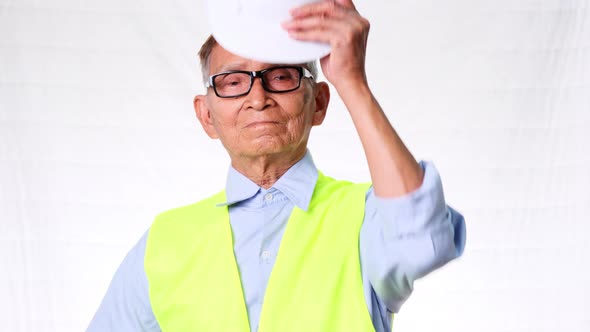 Confident senior engineering architect wearing vest and helmet on white background in studio.