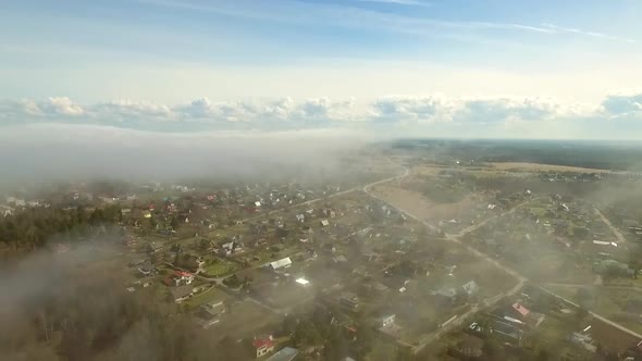 Aerial view of small town with houses and a misty forest in Estonia.