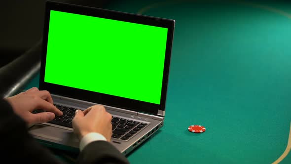 Man Using Online Betting Services on Laptop, Holding Lucky Chip, Green Screen