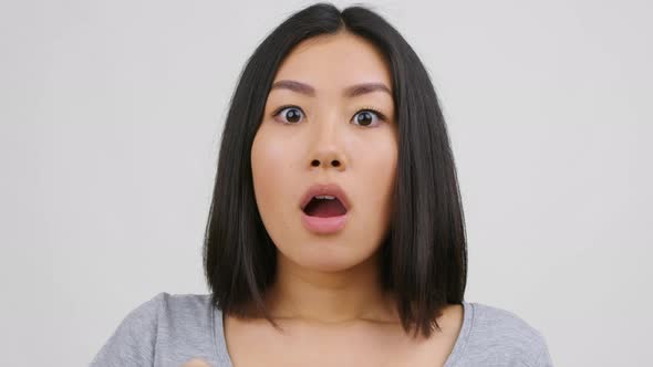 Shocked Asian Female Eating Potatoes Chips On White Studio Background