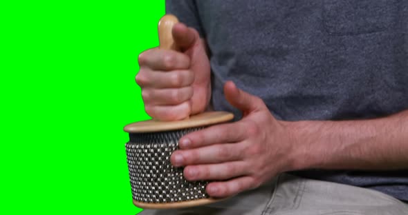 Mid section of male musician playing cabasa