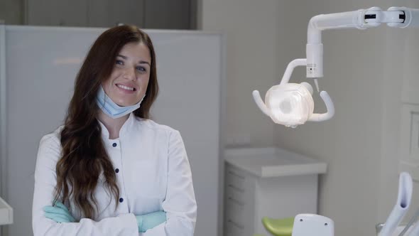 Female Dentist in Uniform Posing Smiling at Camera with Crossed Hands in Clinic