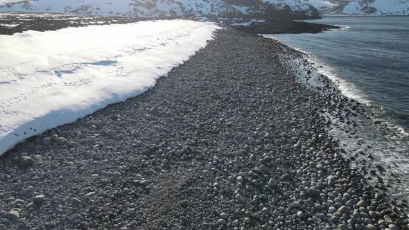 Winter Aerial Flight Top Over Waves Rolling on Artic Ocean Shore with Round Stones Ocean Waves at