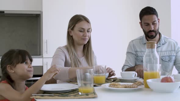 Young Parents and Little Girl Having Breakfast Together