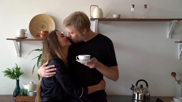 Gentle Middle-aged Man and Woman Look at Each Other, Hug and Communicate, Sitting in the Kitchen in