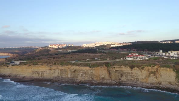 Ericeira drone aerial view on the coast of Portugal with surfers on the sea at sunset