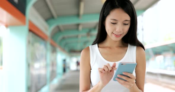 Woman using mobile phone and walking in the light rail station 