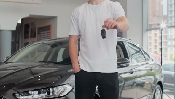 Cropped Shot of a Midsection of a Male Customer Holding Out Car Keys To His Newly Bought Car. Man