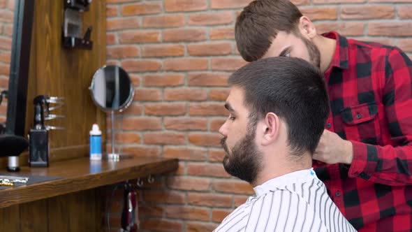 Young Stylish Hairdresser Cuts a Client's Hair in a Barbershop