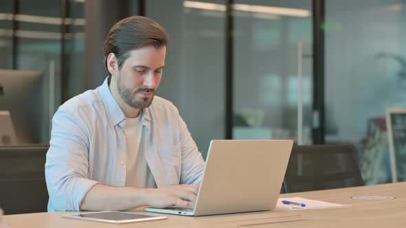 Thumbs Up By Mature Adult Man with Laptop in Office