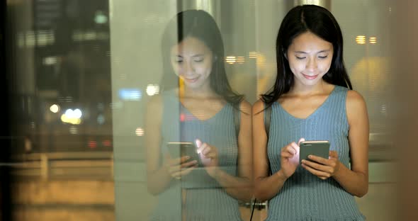 Woman working on smart  phone in the city at night 