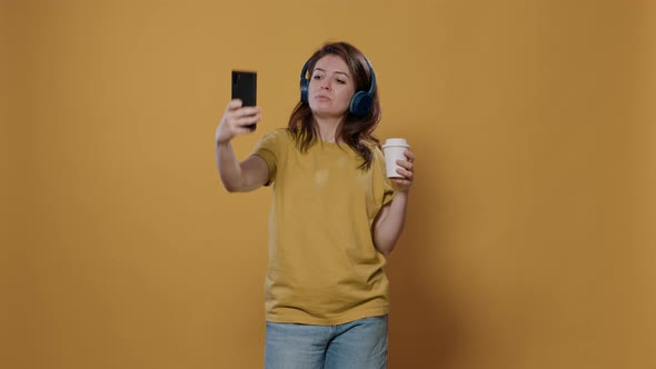 Portrait of Relaxing Woman Taking a Selfie While Holding a Cup of Coffee to Go While Listening to