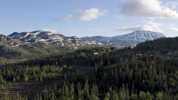 Slow push out with mountain cabins in front of snow covered mountain range drone 4K