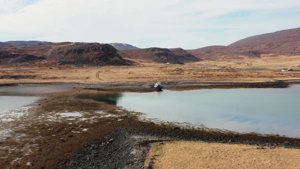 Drone Over Moored Boat In Fjord With Car In Hilly Landscape