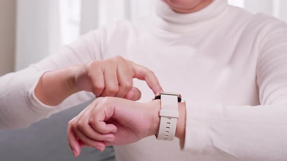 Close up shot of a woman hand who touch and scrolling on a smartwatch in order to quickly check appl