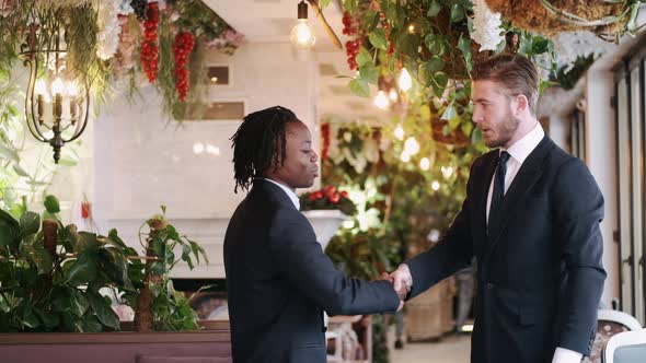 Two Officialy Dressed Businessmen Shake Hands at Beautiful Restaurant