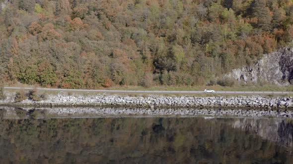 Car Reflected in the Calm Waters of a Fjord in the Fall