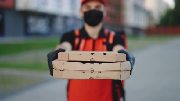 Delivery Man in Gloves and Medical Mask Standing at Street Holding and Handing Carton Boxes