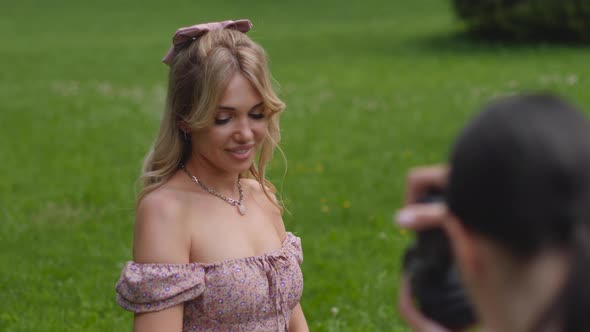 Photographer Takes Pictures of a Girl Lying a Beautiful Woman in a Green Meadow Who Holds a Bouquet