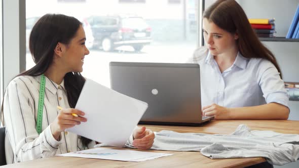 Female Fashion Designer Showing Her Sketches To a Colleague