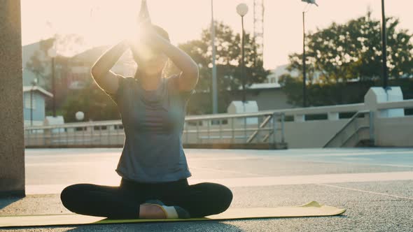 Beautiful young female practicing yoga, sitting in padmasana on a yoga mat.