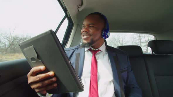 Positive Businessman Enjoying Music in Headphones in Vehicle