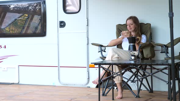 Woman Sitting on Folding Chair Enjoy Evening on Camp Site Next to Camper RV