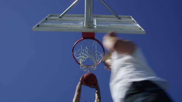 Low angle slow motion shot of man making a slam dunk