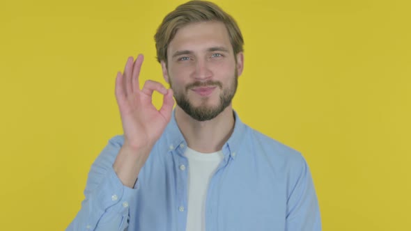 Young Man with Ok Sign on Yellow Background