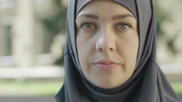 Close-up Face of Confident Attractive Muslim Woman in Hijab Looking at Camera Outdoors. Portrait of