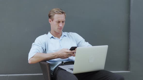 Handsome Blond Man Looks at Modern White Laptop Display