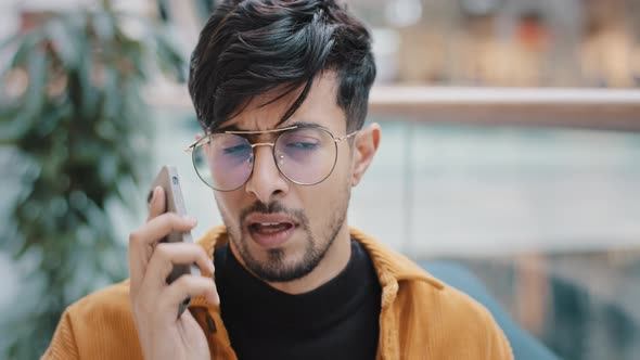 Portrait Worried Annoyed Young Arab Man Standing Indoors Talking on Telephone Answering Call Using