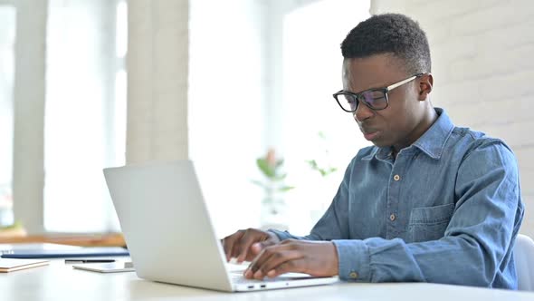 Hardworking Young African Man with Laptop Having Headache