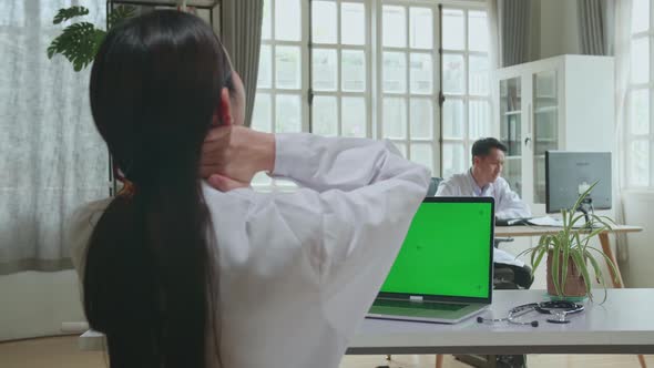 Asian Woman Doctor Is Using Laptop With Mock Up Green Screen Display And Headache In Workplace