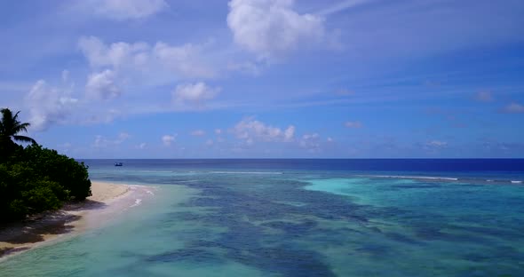 Wide flying tourism shot of a sunshine white sandy paradise beach and turquoise sea background in 4K