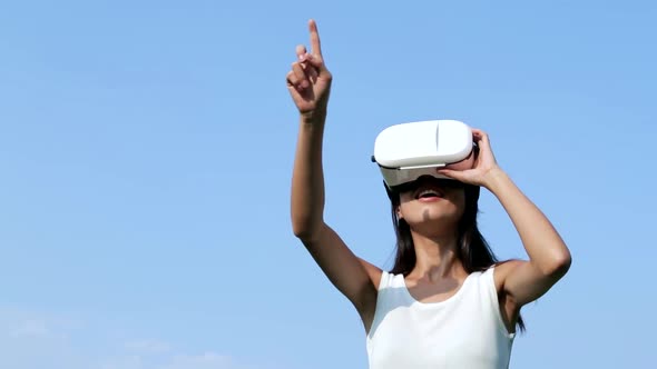 Woman watching with VR device over blue sky 