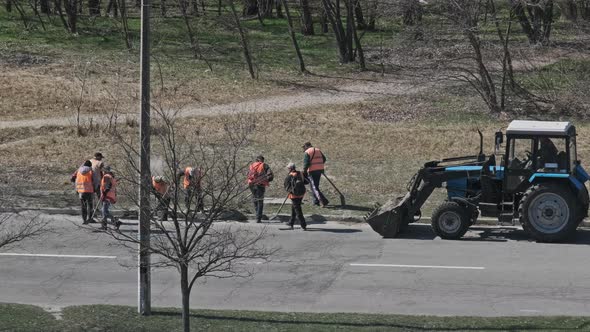 Road Workers Clean the Sides of the Asphalt Road