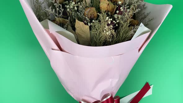 Romantic composition of dried flowers. Dried roses in slow motion on a green background.