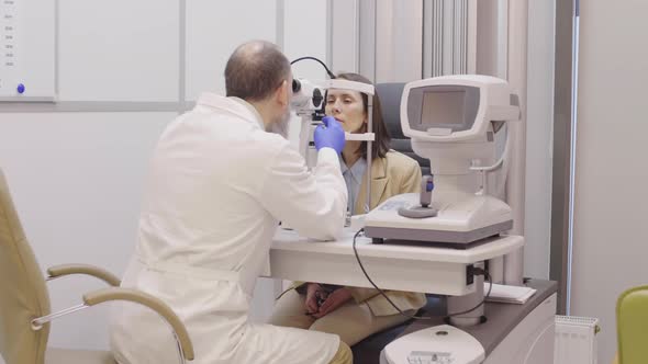 Male Optometrist Using Slit Lamp for Eye Test of Female Patient