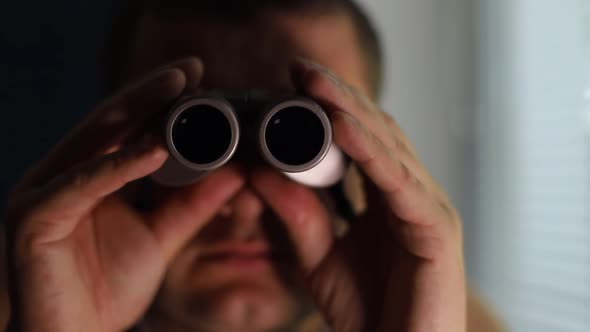 Man Spying on People Using Binoculars for Observation