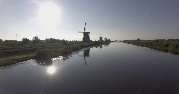 A drone shot panning backwards, around Dutch Windmills during sunrise