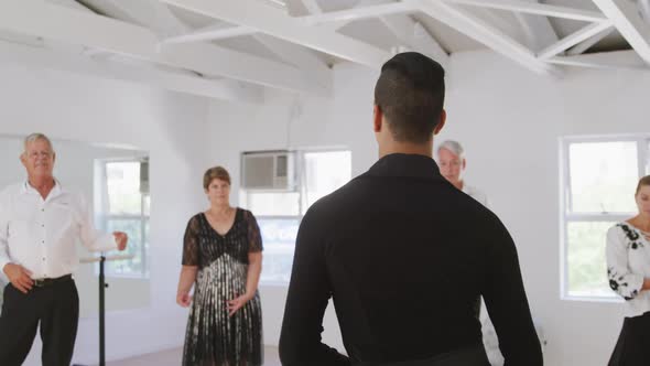 mixed race male dance teacher taking a ballroom dancing class at a dance studio