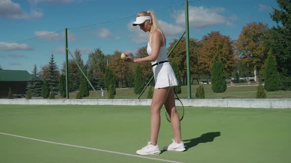 Professional Tennis Player Hits a Ball Off the Floor in a Outdoor Court Low Angle View Young Woman
