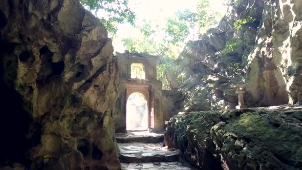 Motion Between Rocky Walls To Stone Arch Against Sunlight